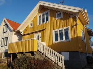 gult trähus med snickarglädje grundmur natursten