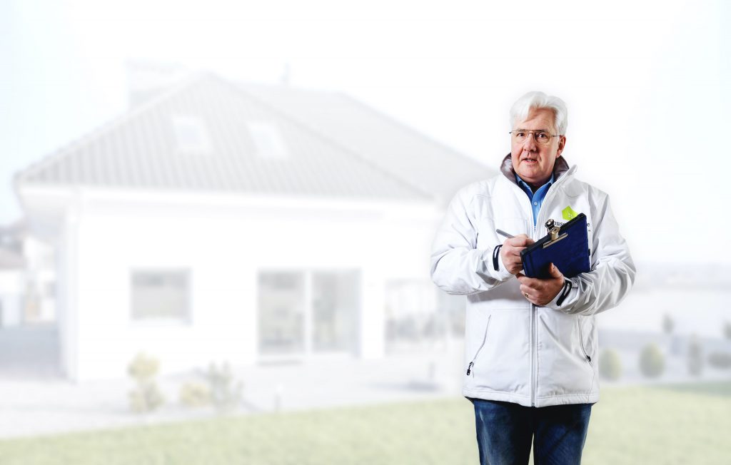 besiktningsman som håller protokoll med vitt hus i bakgrund